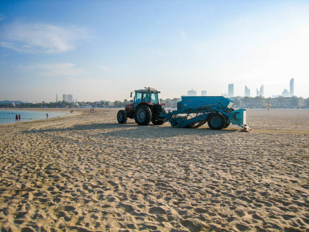 istock tractor picking up trash on the sandy beach in Dubai, UAE at dawn 891569258