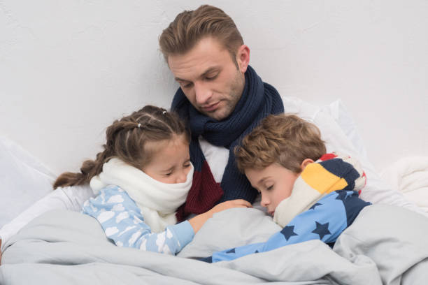 istock Sick father with son and daughter in bed 891576528