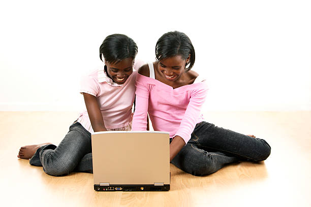 Sisters on laptop 2 stock photo