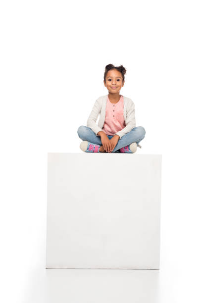 beautiful african american child adorable african american child sitting on cube and smiling at camera isolated on white girl sitting stock pictures, royalty-free photos & images