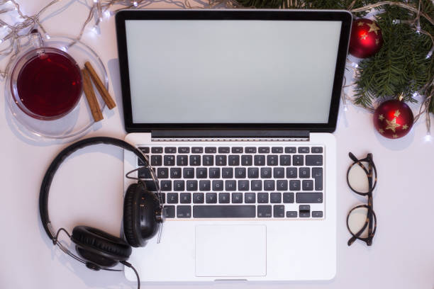 istock Top view office table desk. Workspace with laptop and christmas decorations on white background xmas lights bokeh glasses phones tea mockup 891597682