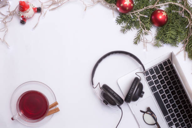 istock Top view office table desk. Workspace with laptop and christmas decorations on white background xmas lights bokeh glasses phones tea mockup 891597686