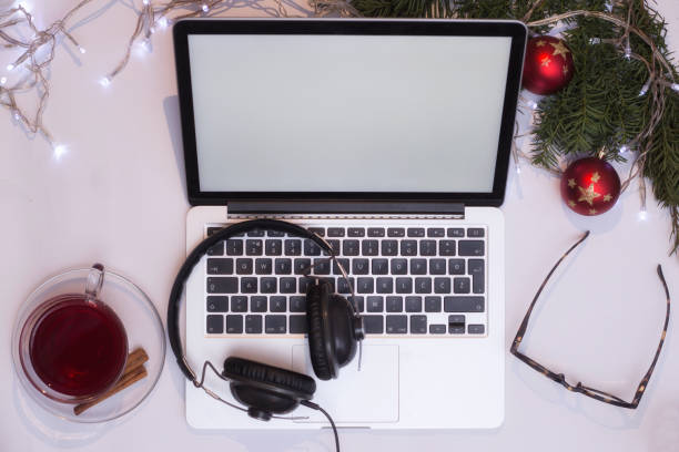 istock Top view office table desk. Workspace with laptop and christmas decorations on white background xmas lights bokeh glasses phones tea mockup 891600058