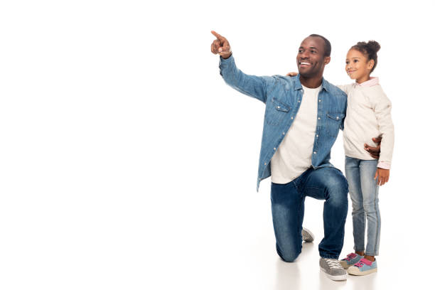 smiling african american father and daughter pointing with finger and looking away isolated on white