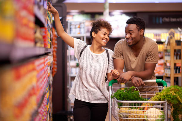 Shopping together for all their essentials Shot of a young couple shopping in a grocery store merchandise stock pictures, royalty-free photos & images