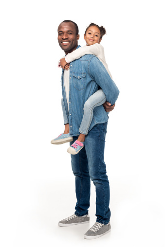 happy african american father piggybacking daughter and smiling at camera isolated on white