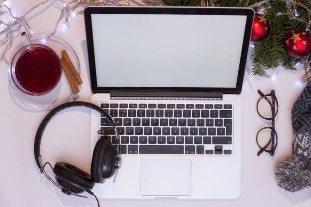 istock Top view office table desk. Workspace with laptop and christmas decorations on white background xmas lights bokeh glasses phones tea mockup 891601860