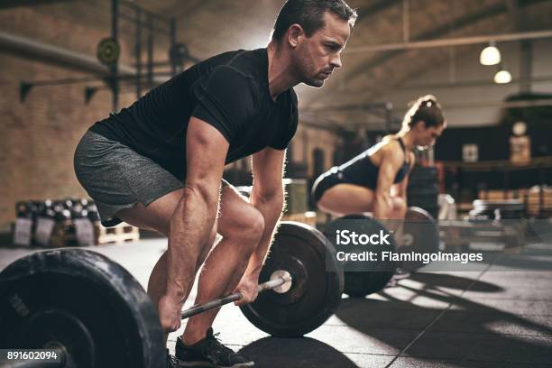 Spotive Man And Woman Lifting Heavy Barbells Stock Photo - Download Image Now - Men, Deadlift, Gym