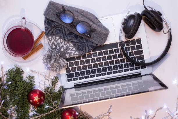 istock Top view office table desk. Workspace with laptop and christmas decorations on white background xmas lights bokeh glasses phones tea mockup 891604258