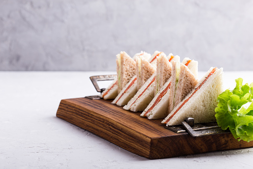 English tea sandwiches platter on wooden board over light background