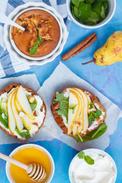istock Sandwiches with cottage cheese, honey, pear, nuts and chocolate cupcakes with mint tea. 891604526