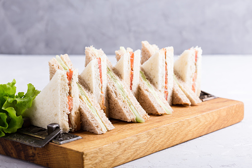 English tea sandwiches platter on wooden board over light background