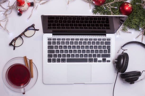 istock Top view office table desk. Workspace with laptop and christmas decorations on white background xmas lights bokeh glasses phones tea mockup 891604978