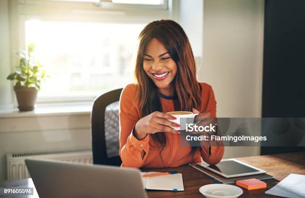 Junge Frau Kaffee Trinken Während Der Arbeit Von Zu Hause Aus Lachen Stockfoto und mehr Bilder von Kaffee - Getränk