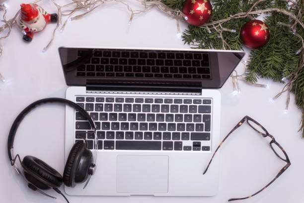 istock Top view office table desk. Workspace with laptop and christmas decorations on white background xmas lights bokeh glasses phones tea mockup 891605702