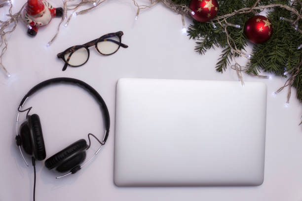 istock Top view office table desk. Workspace with laptop and christmas decorations on white background xmas lights bokeh glasses phones tea mockup 891605706