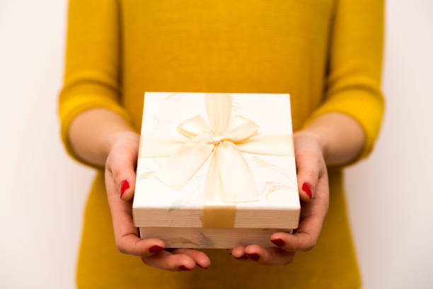 istock Woman holding in hands white gift box with golden bow 891608810