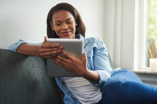 istock Young African woman sitting at home using a digital tablet 891609164