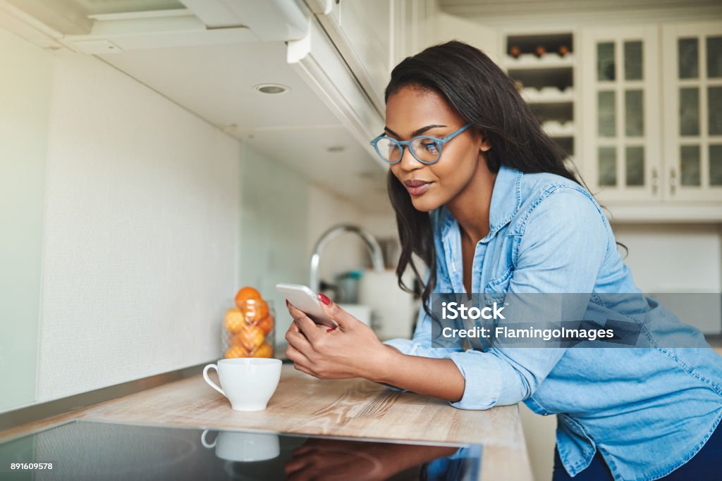 Giovane donna africana che beve caffè e sms al cellulare - Foto stock royalty-free di Donne