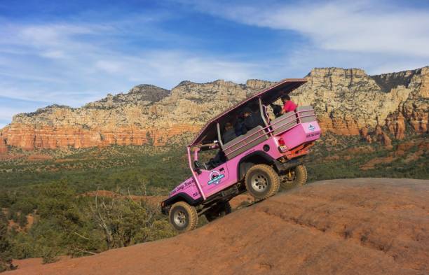 Pink Jeep Terrain Vehicle with Tourists on Sedona Slick Rock Pink Jeep Off Road Terrain Vehicle touring Broken Arrow Slick Rock with Tourists onboard red rocks state park arizona photos stock pictures, royalty-free photos & images