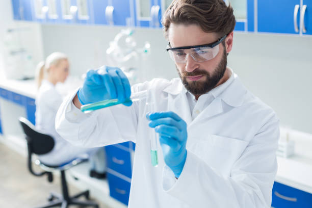 istock Serious professional chemist pouring liquid into the different test tube 891619542