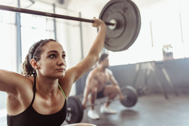 istock Tough young woman exercising with barbell 891619550