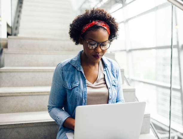 istock Young African student sitting on stairs prepping for an exam 891624994
