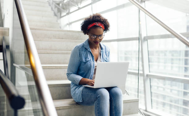 istock Young African student sitting on campus stairs using a laptop 891625050