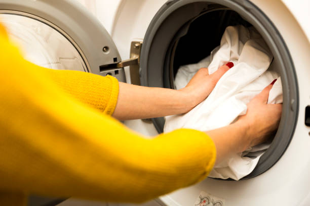 istock Woman hand loading dirty clothes in washing machine 891625078