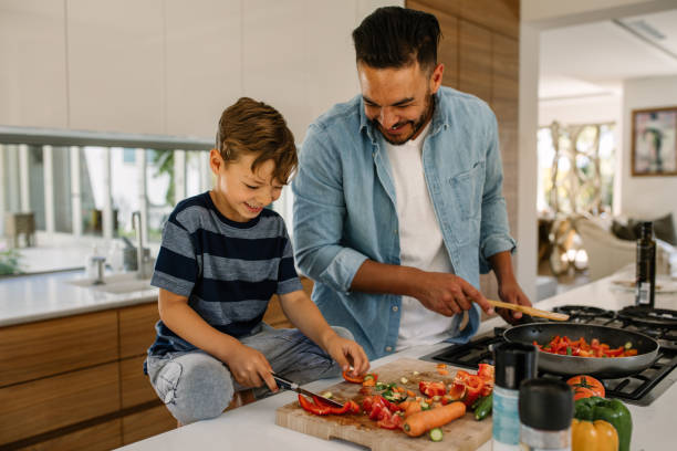 père et fils, préparation des repas dans la cuisine - cuisiner photos et images de collection