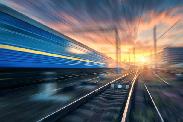 istock Railway station with motion blur effect. Blurred railroad. Industrial conceptual landscape with blurred railway station, speed train, blue sky with colorful clouds and sun. Railway track. Background 891632038