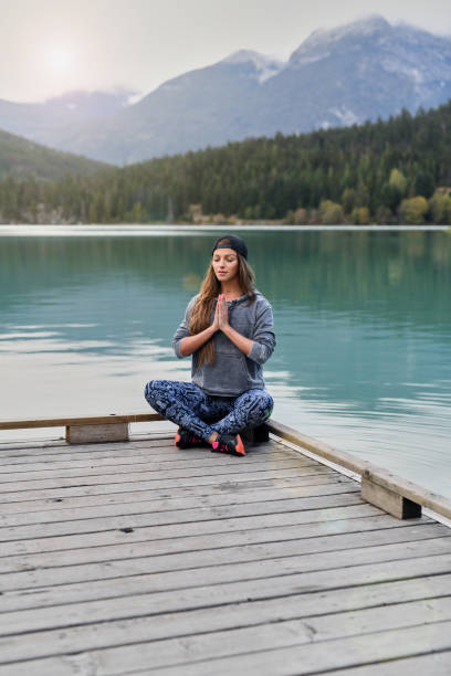 istock Young woman meditating over lake and mountain background 891632074