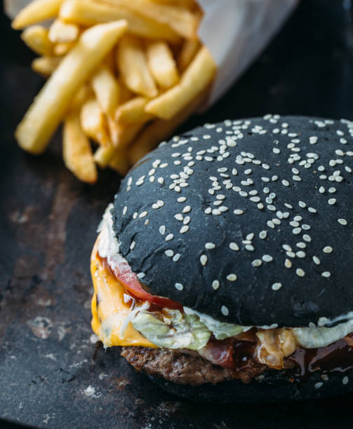 istock Black burger with meat, cheddar cheese and vegetables. Rustic style 891634830