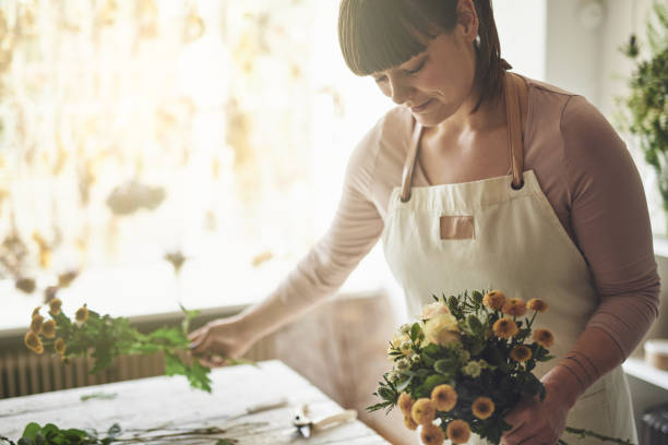 istock Smiling florist making a bouquet in her flower shop 891634944
