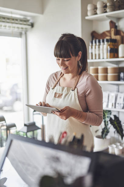 istock Smiling female florist using a tablet in her flower shop 891635146