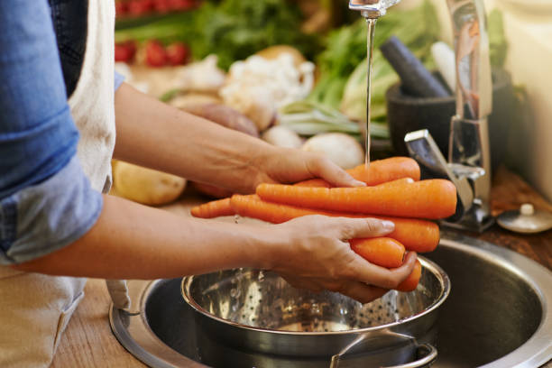 The beginnings of something delicious Cropped shot of an unrecognizable woman rinsing vegetables at home food hygene stock pictures, royalty-free photos & images