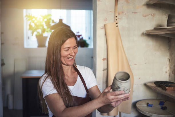 istock Smiling female artisan inspecting a vase in her creative workshop 891653692