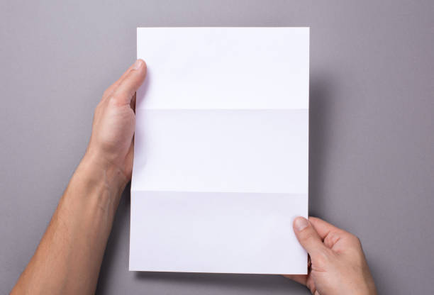 istock Man holds an open blank letter mock-up and an envelope on a gray background 891662610