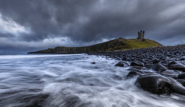 istock Waves crashing on basalt boulders around Dunstanburgh castle 891662704