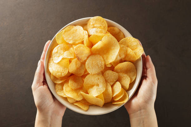 manos dando plato de patatas fritas sobre fondo marrón. - utensilio para servir fotografías e imágenes de stock