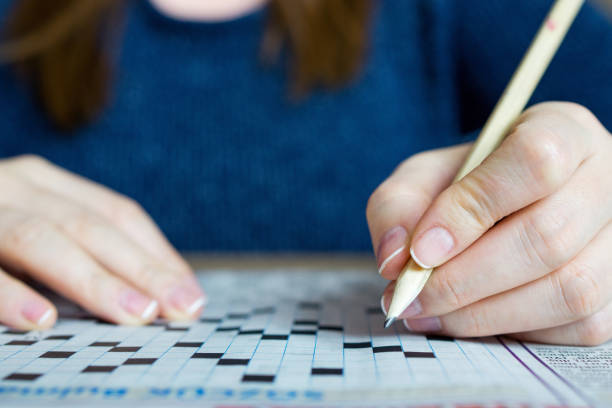 istock Female hand holding a pencil and solves crossword puzzle 891692192