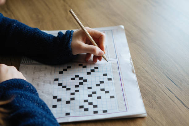 istock Female hand holding a pencil and solves crossword puzzle 891694526