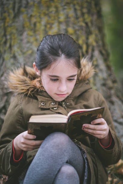 istock Adorable schoolgirl reading a book. 891695158