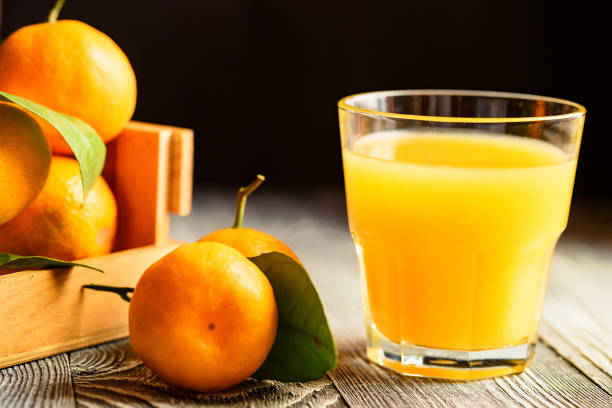 istock Glass of fresh juice and mandarins on table 891707798
