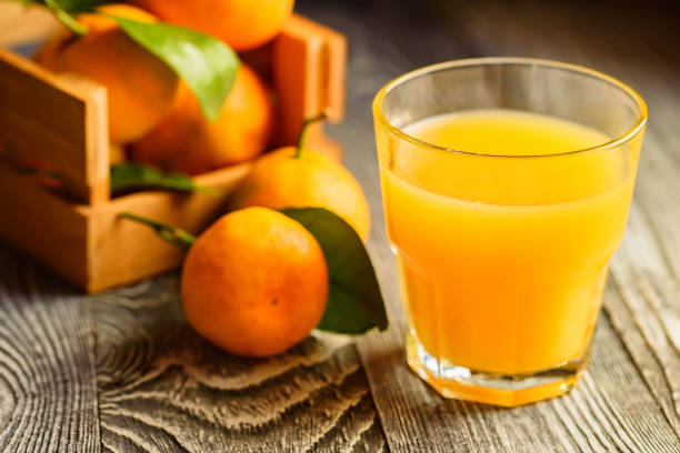 istock Glass of fresh juice and mandarins on table 891707970