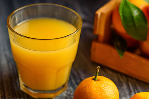 istock Glass of fresh juice and mandarins on table 891712192