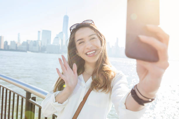 istock Young woman waves during selfie on city pier 891713288
