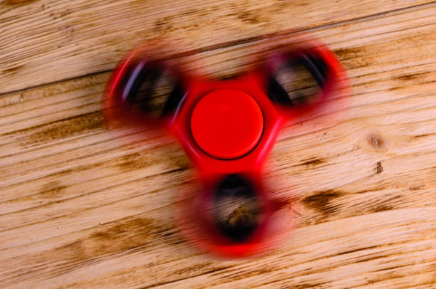 istock Red fidget spinner rotates on wooden desk 891729732