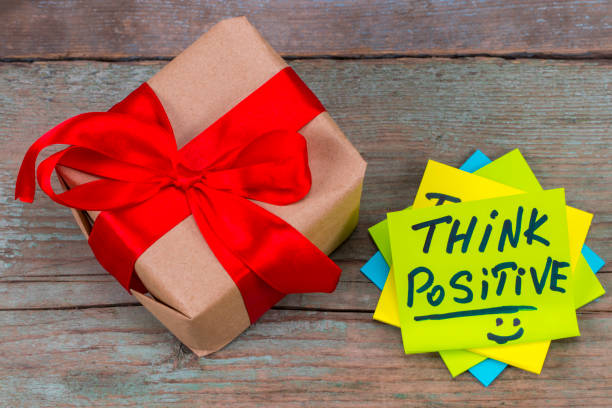 istock think positive - inspirational handwriting in a green sticky note  and gift with red ribbon on wooden background 891732984