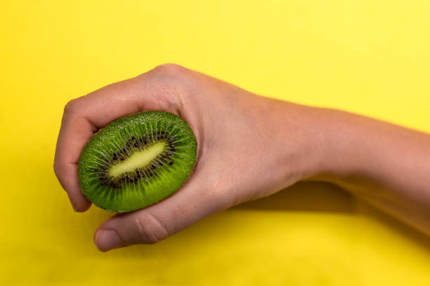 istock Hand holding kiwi, isolated on yellow background 891782236